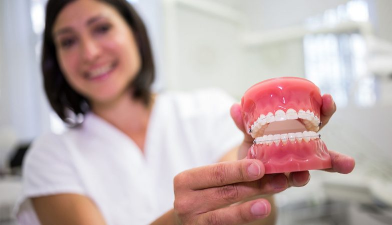 The dentist holds the denture for a photograph.